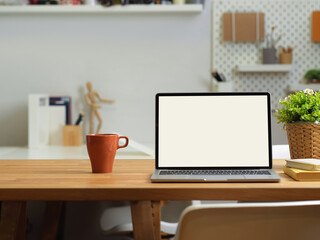Close up view of office desk with laptop, mug, stationery and supplies on table