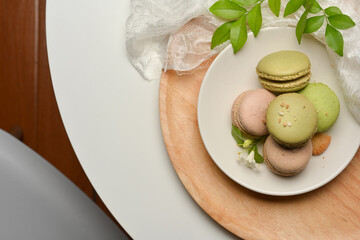 A plate of French Colorful Macarons on coffee table decorated with leaves