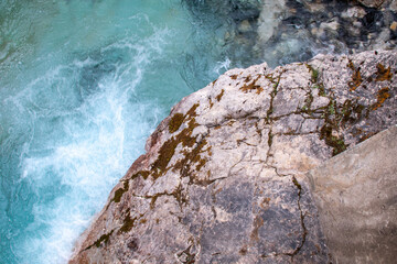 Johnston Canyon, Banff, Alberta, Canada - August 2020: Swirling blue pool of turquoise water with a mossy gray rock in the foreground (Rocky Mountains).