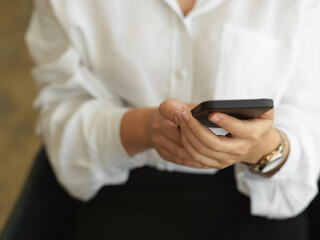 Female hand using smartphone while sitting in office room