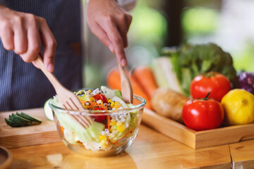 Closeup image of a female chef cooking fresh mixed vegetables salad in kitchen