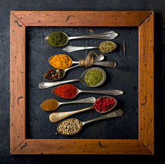 Various spices spoons on black table. Top view with copy space