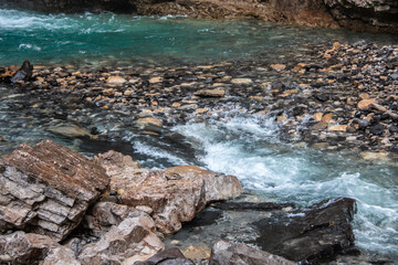 August 2020: Shallow turquoise water rapids at the base of Johnston Canyon's upper falls in Banff, Alberta, Canada, August 2020. 