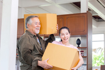 Asian senior father and young daughter carrying boxes into new home, Happiness family on moving day...