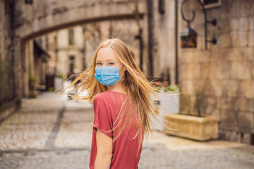 Young woman wearing a medical mask during COVID-19 coronavirus tourist walks down the street in a European city after the end of COVID-19 coronavirus. quarantine