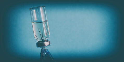 The concept of vaccination. Close-up, banner. An ampoule of medicine, turned upside down, and five medical needles from syringes stuck in the bottle cap