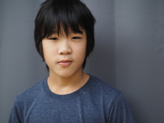 Funny portrait of 11 years old asian boy with dark blue t shirt	