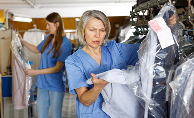 Two women in uniform working at dry-cleaning salon