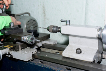 A man sets up a lathe for processing a part.