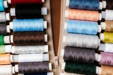 Many different reels with threads, flat lay, top view. Colored threads, close-up, bright background. Cutting and sewing clothes concept. Accessories for needlework