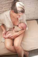 Mother holding newborn baby and breastfeedidiing little infant kid in hands