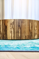 Elegant contemporary textured round coffee table made of plywood and Black Ofram natural veneer on blue carpet in room closeup
