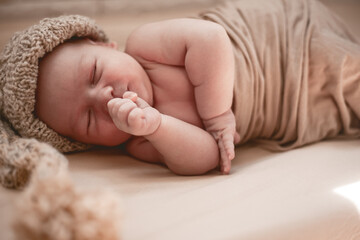 Newborn sleeping baby in knitted hat lies on the blanket .