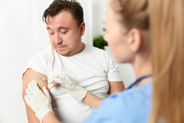 a woman doctor injects a vaccine into a man's hand close-up