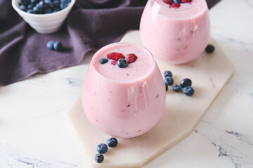 Glasses of tasty smoothie with blueberry and raspberry on light background