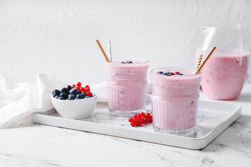 Glasses of delicious smoothie with blueberry and cranberry on light background