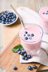 Glasses of yummy blueberry smoothie and mint on wooden background