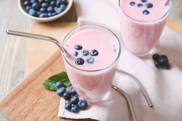 Glasses of yummy blueberry smoothie and mint on wooden background