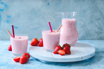 Glasses and jug with yummy strawberry smoothie on color background