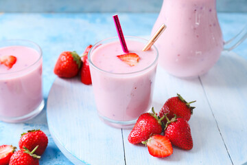 Glasses and jug with yummy strawberry smoothie on color background