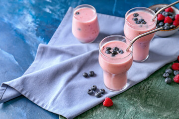 Glasses of tasty smoothie with blueberry and raspberry on color background