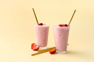 Glasses of yummy strawberry smoothie on light background
