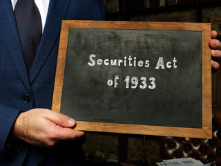 Young man holding a card in hands. Conceptual photo about Securities Act of 1933 with written text.