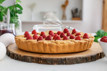 Tasty raspberry pie on wooden board in kitchen, closeup
