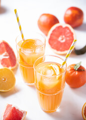 Citrus juice in two glasses and fresh fruit tangerine, orange, grapefruit and lemon on a  white background