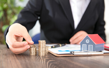 Real estate practitioners stack coins and tables on the small house model and related documents