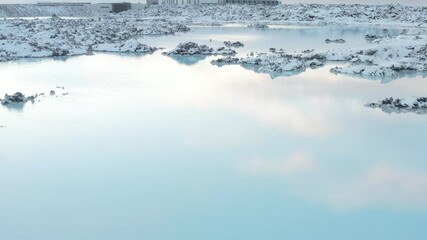Stunning blue lagoon pools reflect sky in snowy rugged landscape of iceland