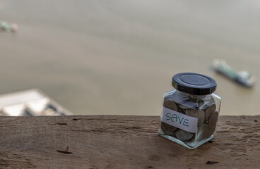 The pile of coins in glass bottle on sky background for concept for growth and saving money. Space...