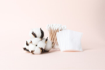 Cotton swabs, cotton pads and cotton on a pink background.