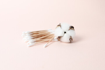Cotton swabs, cotton pads and cotton on a pink background.