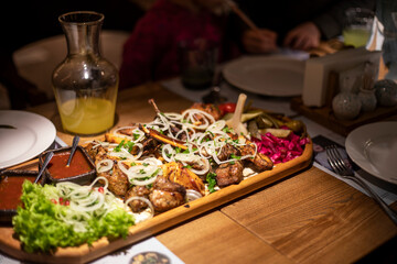 set of mixed meat with salad and sauce on a board with lemonade for a company, horizontal
