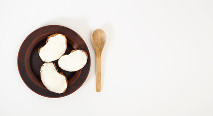 Banner with a healthy snack made from whole grain baguette and natural curd cheese cream on a white background. Healthy food. Proper nutrition. Copy space, flat lay, top view
