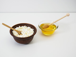 Diet breakfast cottage cheese with honey. Natural flower honey with honey dipper. Farm cottage cheese in handmade earthenware bowl on white background