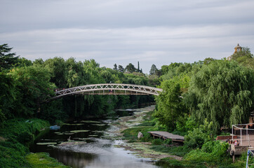 Puente sobre un r&iacute;o, con naturaleza alrededor. Cielo nublado