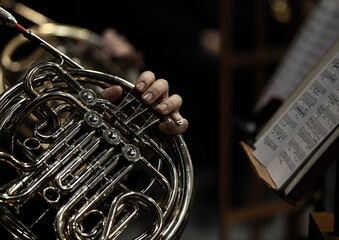Hands of a musician playing the French horn in the orchestra close up