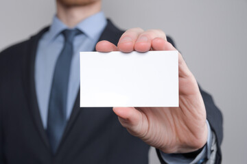 Businessman ,Business Man's hand hold showing business card - close up shot on grey background. Show a blank piece of paper. Paper visit card