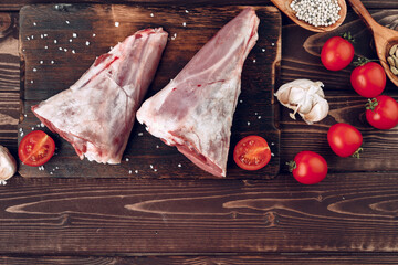 Raw lamb leg on dark wooden board