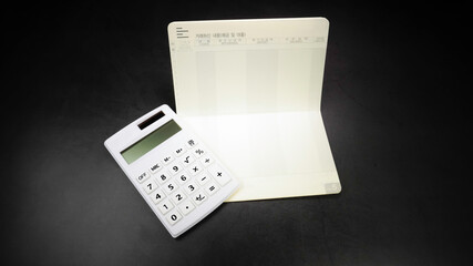 Saving Account Bankbook and Calculator on Black Background. Translation: Transaction details (deposit and loan), Order. Money and Bank Concept