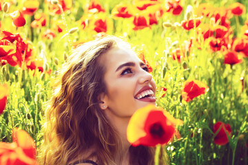 Naklejka premium Spring blossom. Facial portrait of sexy female model. Beautiful woman on poppy field with smiling face.