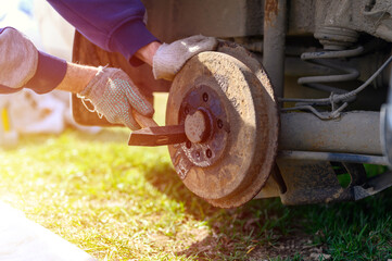 men's gloved hands repair of car drum brake himself. disassembles a jammed disk with a hammer. repair of broken car drum brake disassembled outdoor. flare
