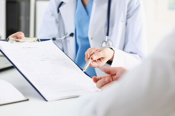 Female doctor hand hold silver pen and showing pad. Physical agreement form signature, disease...