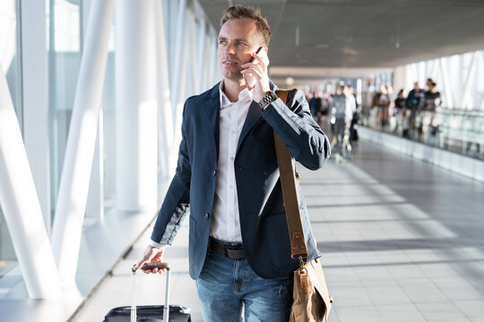 Young man walking through airport gate and talking on phone