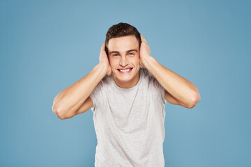 Fototapeta premium cheerful man in a white t-shirt gesturing with his hands emotions blue background
