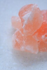 Pink himalayan salt pieces close-up on a  marble background.Pink crystal salt