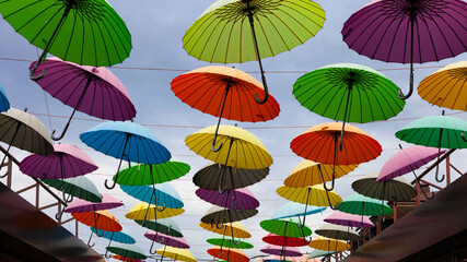 Fototapeta na wymiar many colorful umbrellas hanging in the sky above the alley