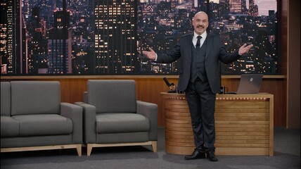 Late-night talk show host is performing his monologue, looking into camera. TV broadcast style show. Model and property released for commercial use.
